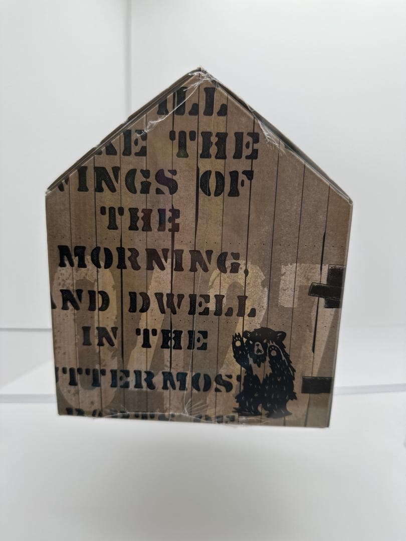 Unedited side-view photo showing the gabled box, printed bear and shrink-wrap creases