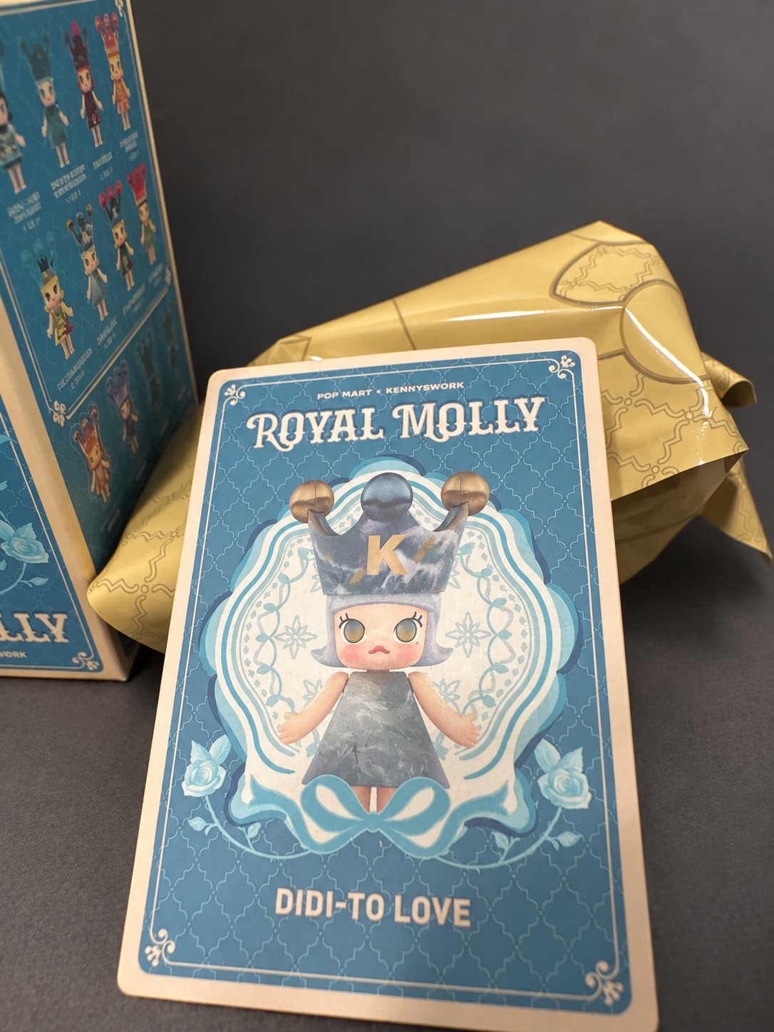 Edited listing photo of DIDI-TO LOVE character card, inner bag and outer box on a dark background