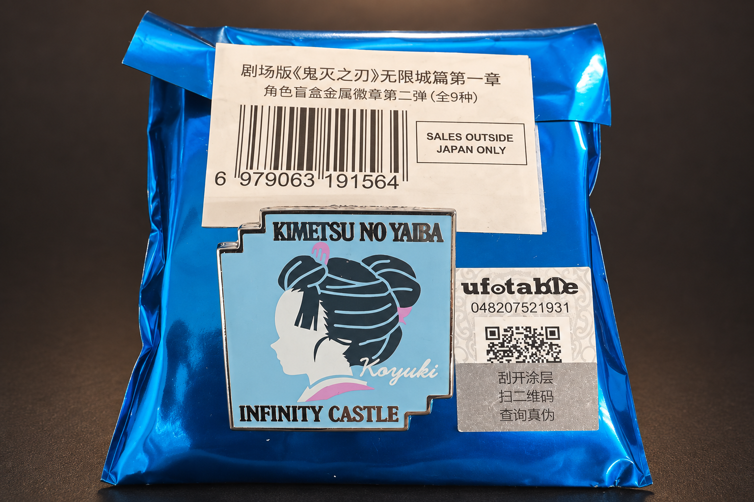 A Demon Slayer Infinity Castle metal pin badge (Koyuki) on its blue blind bag