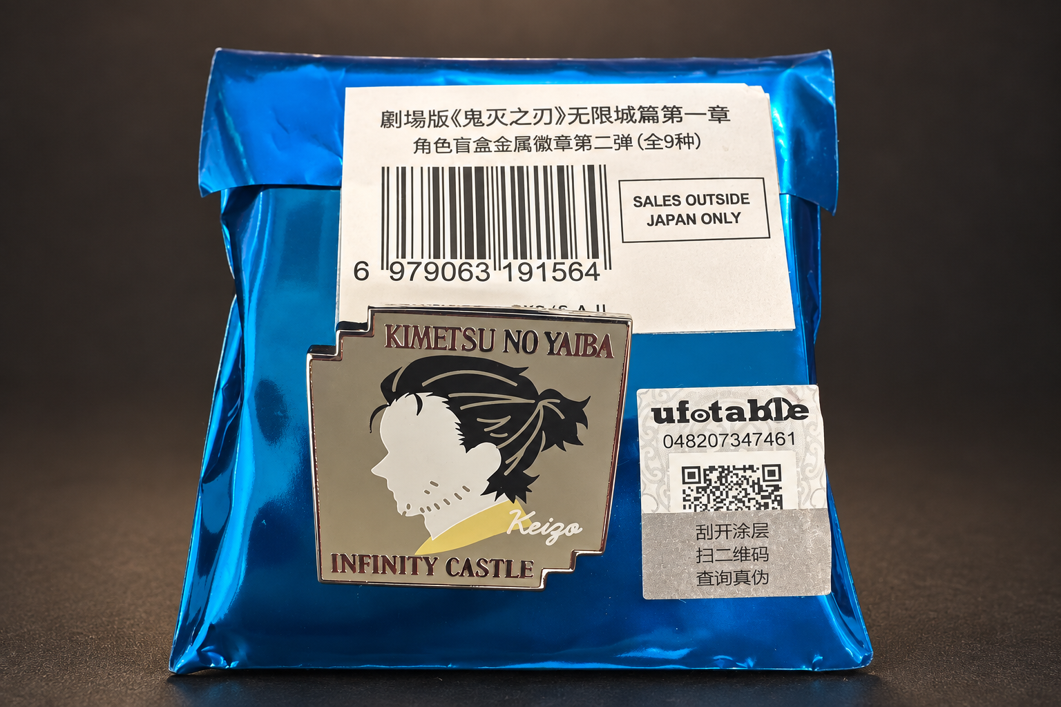 青い袋の上に置かれた鬼滅の刃 無限城編のメタルピンバッジ（慶蔵）