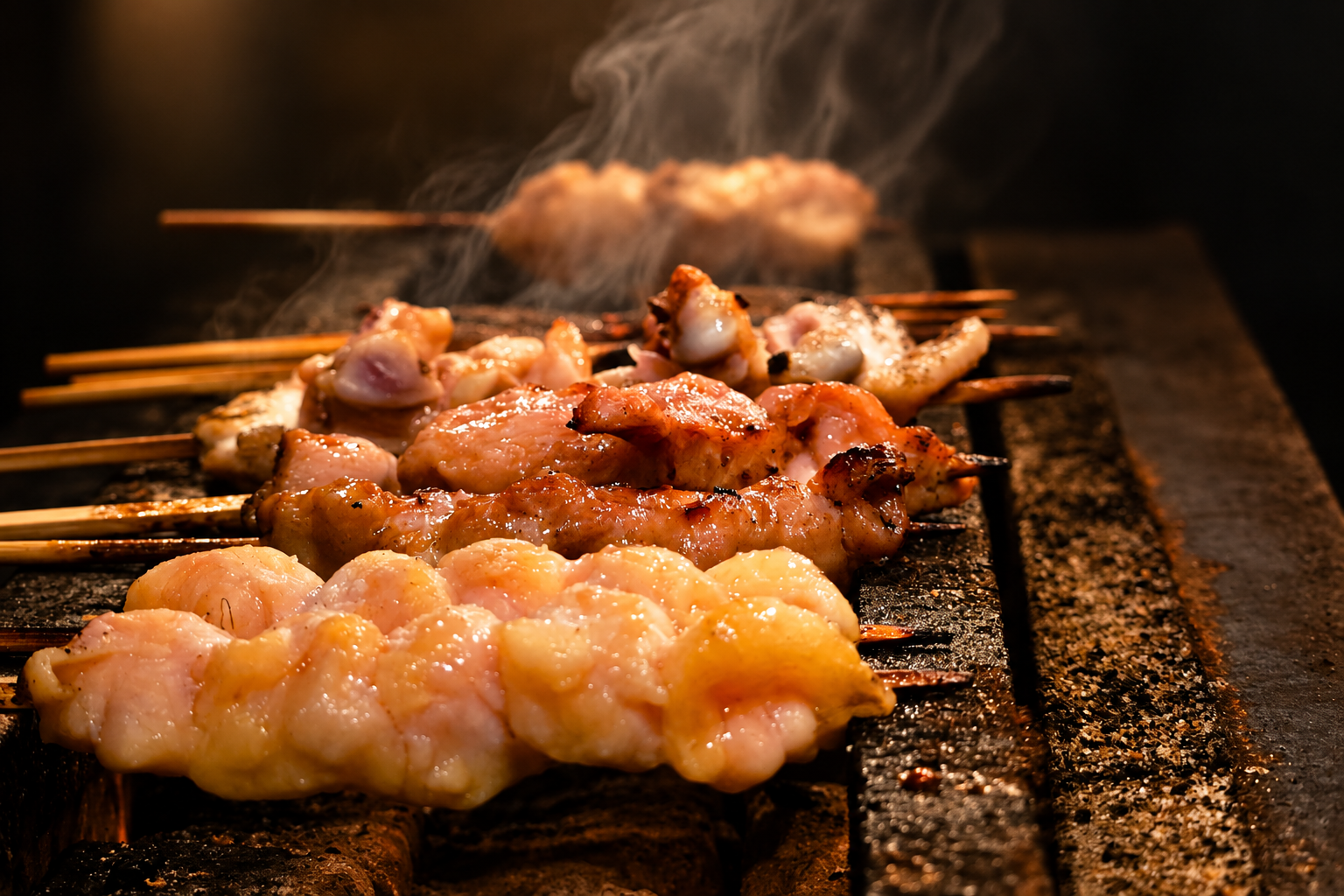 焼鳥千吉の炭火の上に並ぶ焼鳥の串と立ちのぼる煙