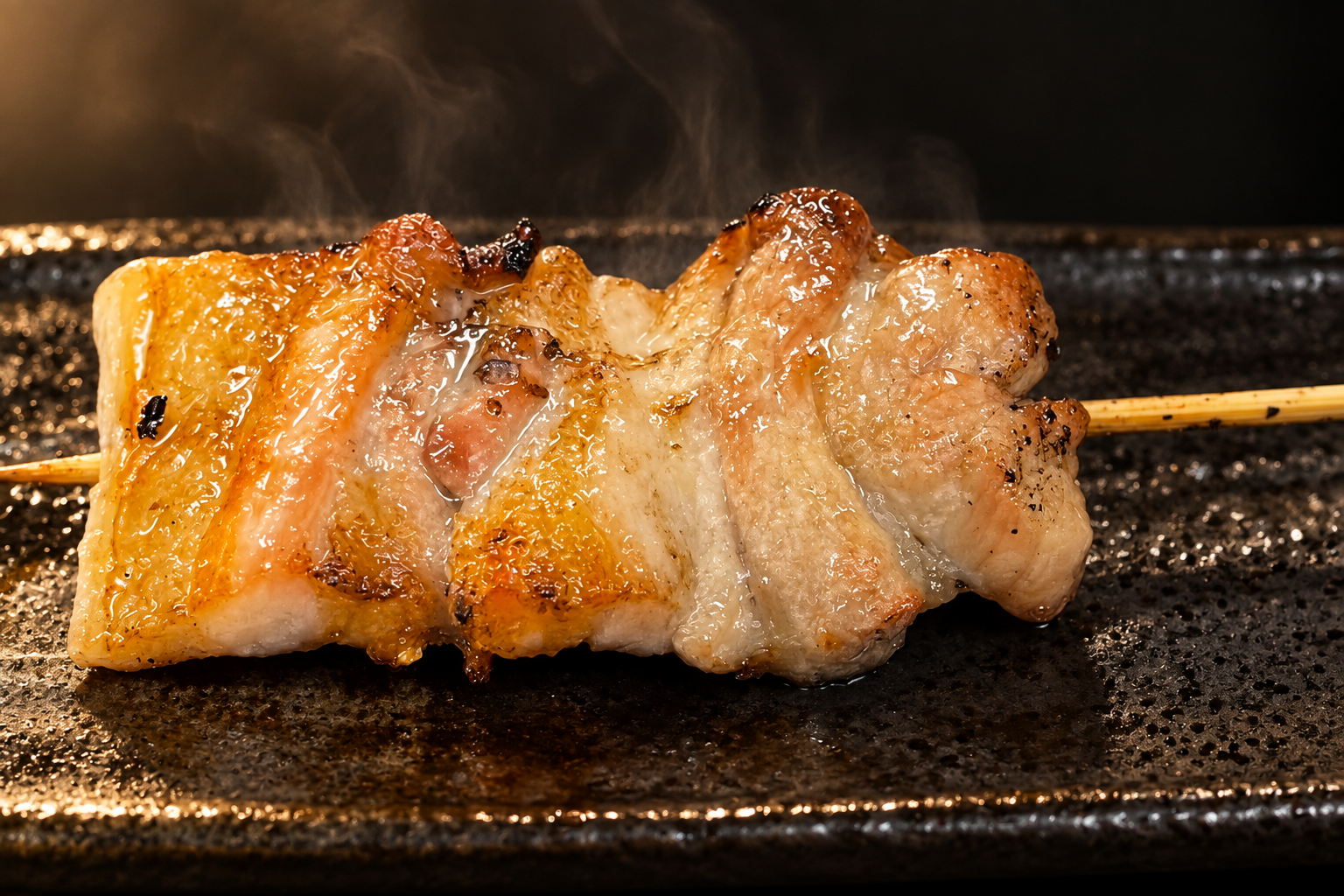 A grilled skewer of layered meat on a dark speckled plate, with light steam rising