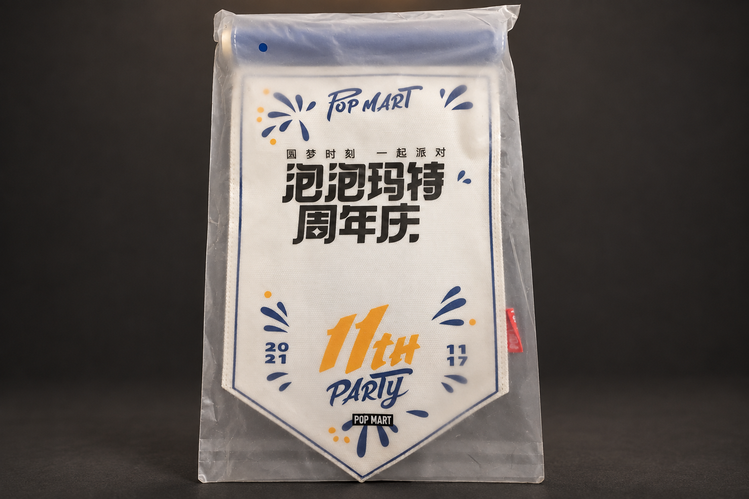 透明な袋に入った白いペナント形のフラッグ。「泡泡玛特周年庆」「11TH PARTY」とPOP MARTのロゴ