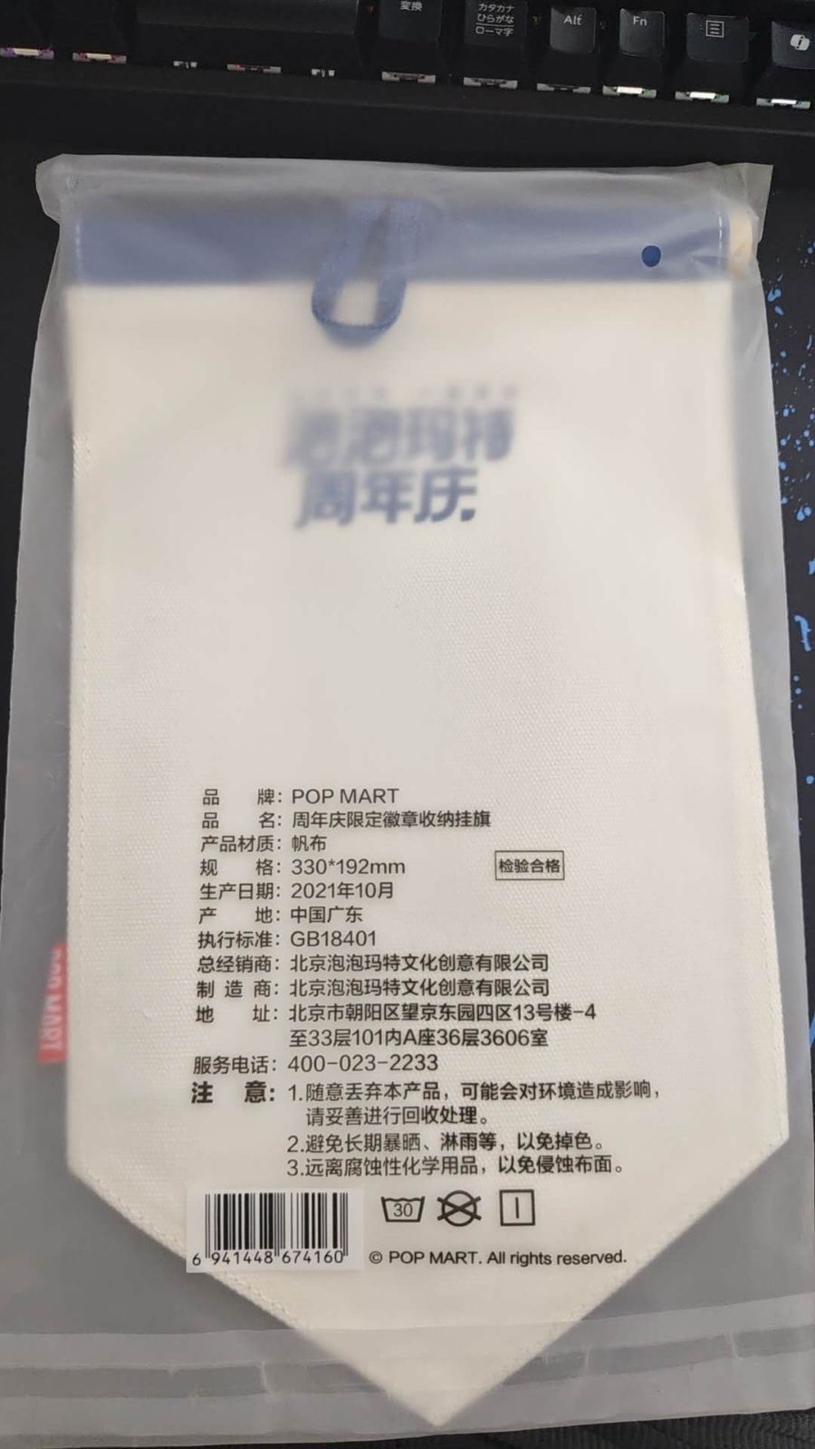 Back of the flag in its clear bag, with a Chinese product label, a barcode and a hanging loop at the top