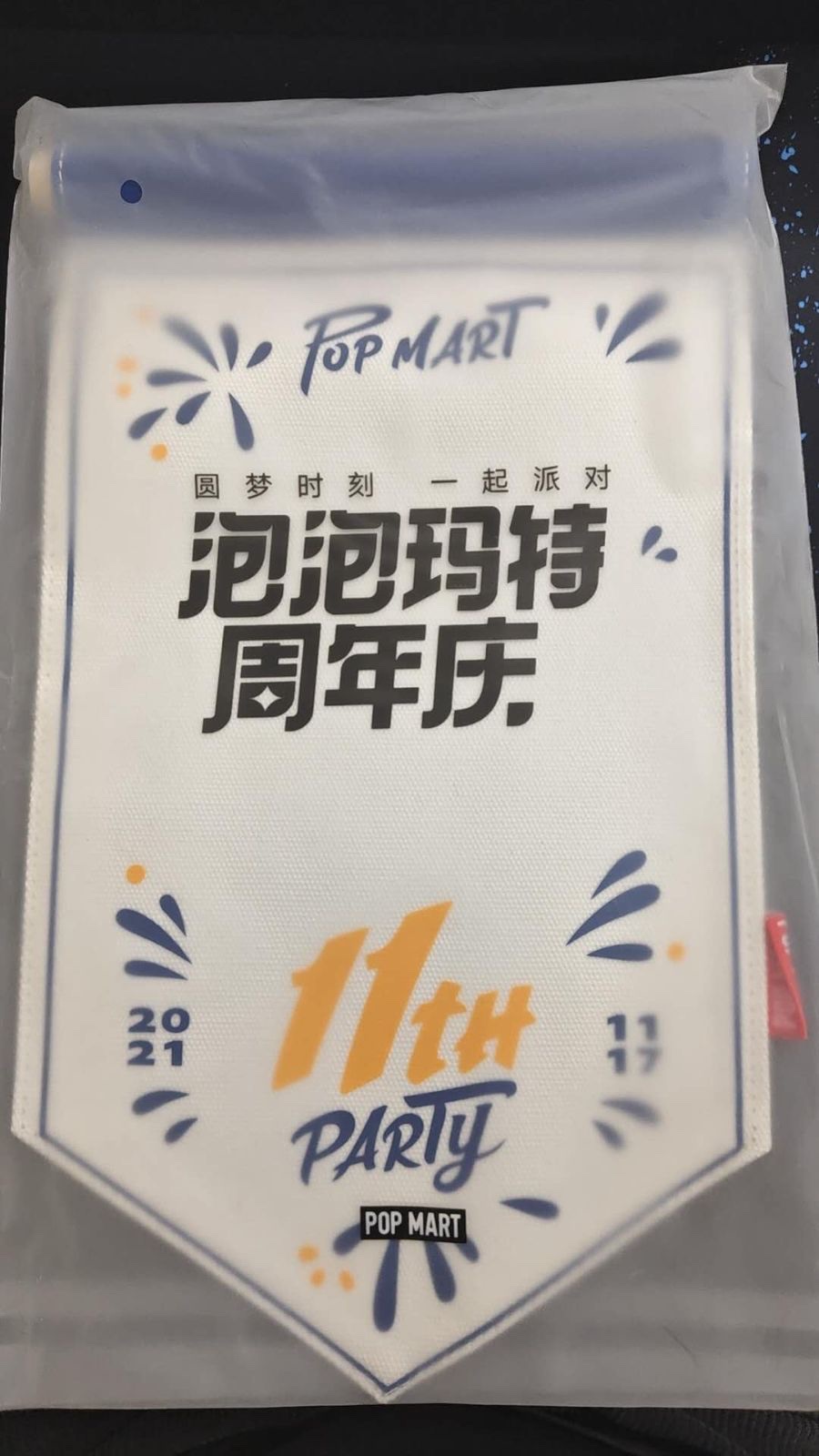 Front of the flag in its clear bag, printed with 泡泡玛特周年庆 and 11TH PARTY
