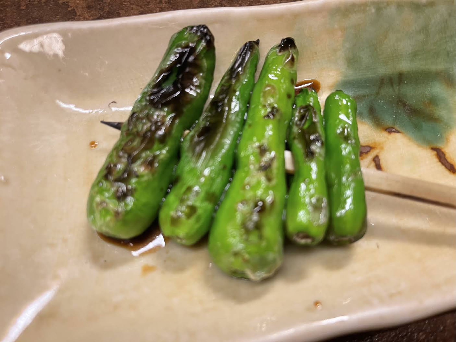 陶器の角皿にのった、焼き目のついたししとう5本の串（未加工の写真）
