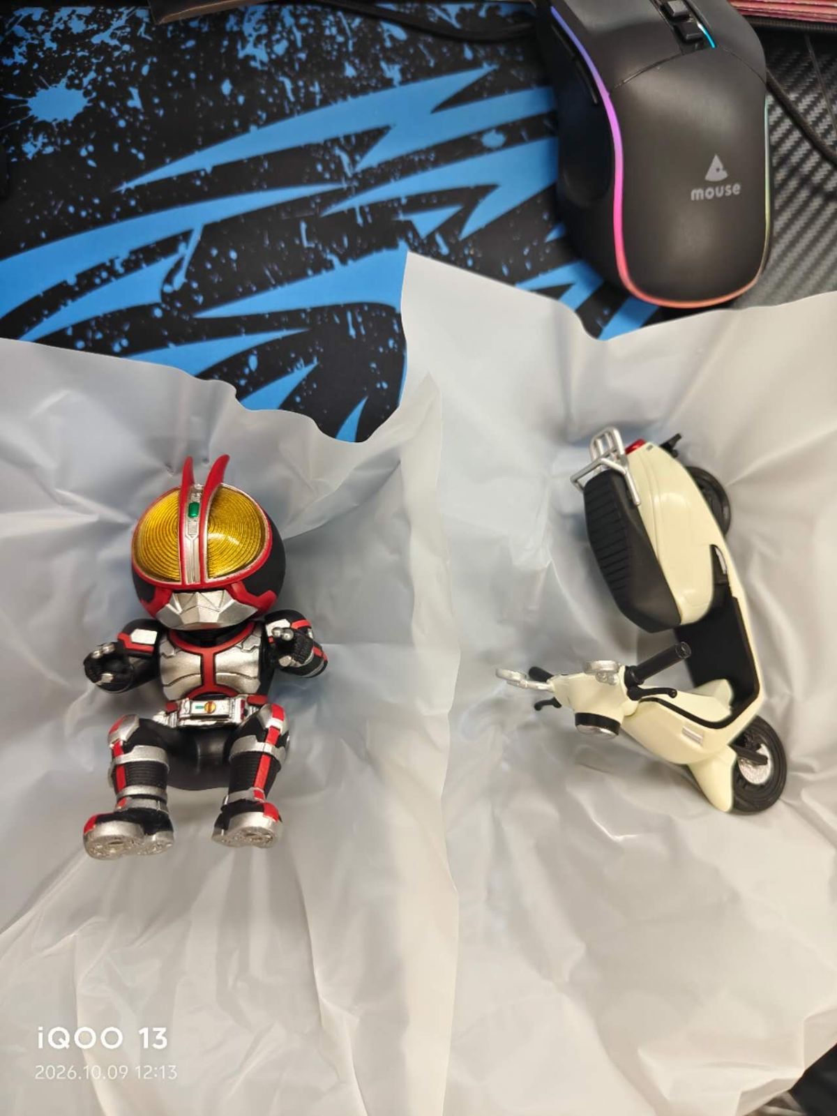 The Kamen Rider Faiz figure and a white scooter-type bike on white tissue paper (unedited photo)