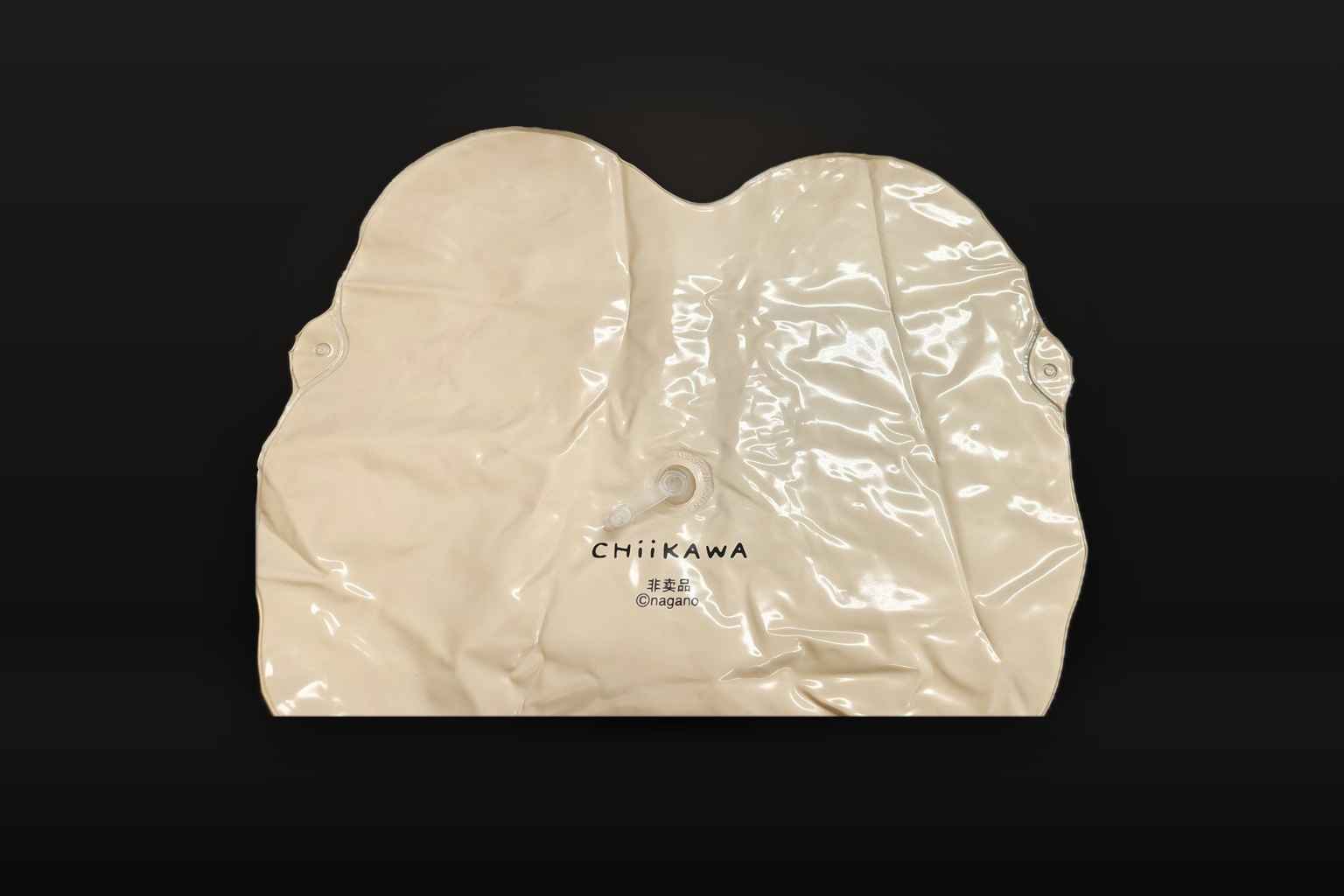 The cream-coloured back of the vinyl bag on a dark background, printed with CHIIKAWA, 非卖品 and ©nagano below a small clear air valve