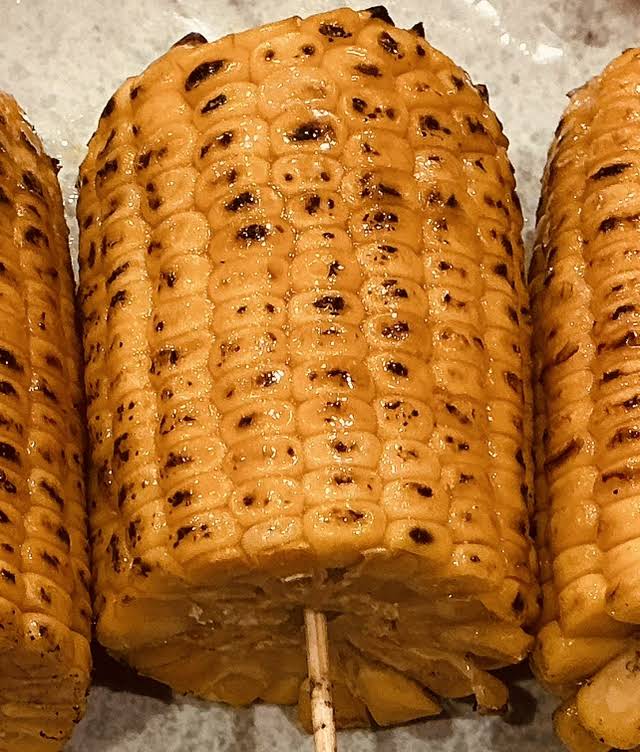 Rounds of corn on bamboo skewers with glossy, charred kernels (unedited photo)