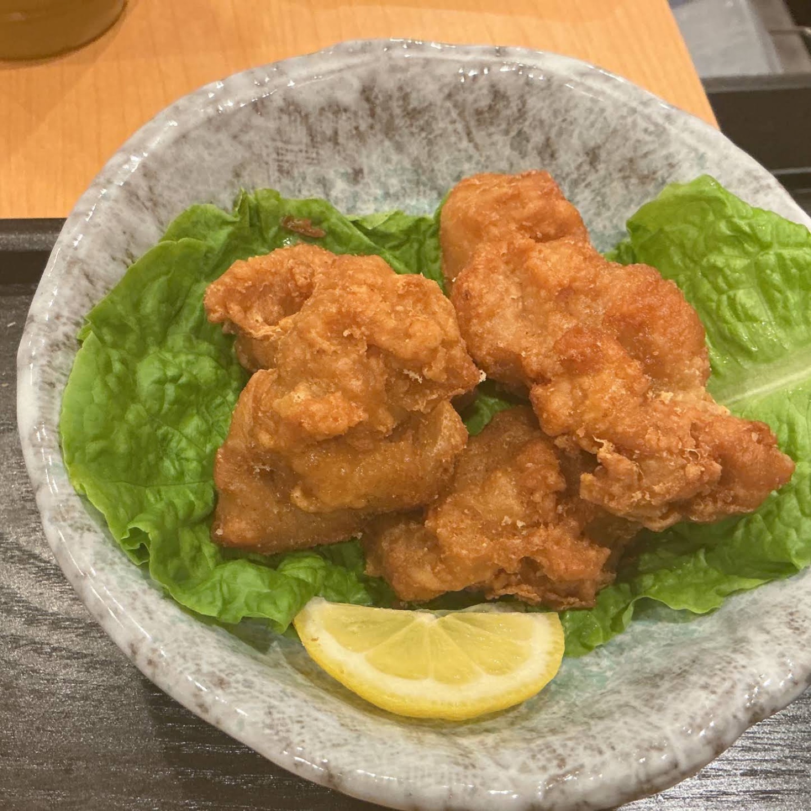 グレーの器にレタスを敷き、鶏の唐揚げとくし形のレモンが盛られている(未加工の写真)