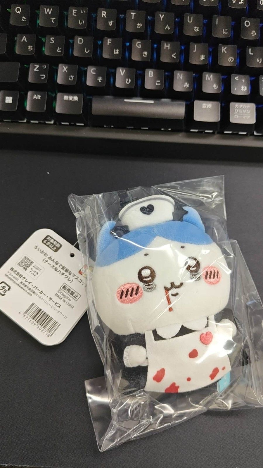 Nurse Hachiware mascot in a clear bag on a black mat, wearing a white nurse cap and white apron, with a white header tag on the left (unedited photo; a keyboard is visible at the top)
