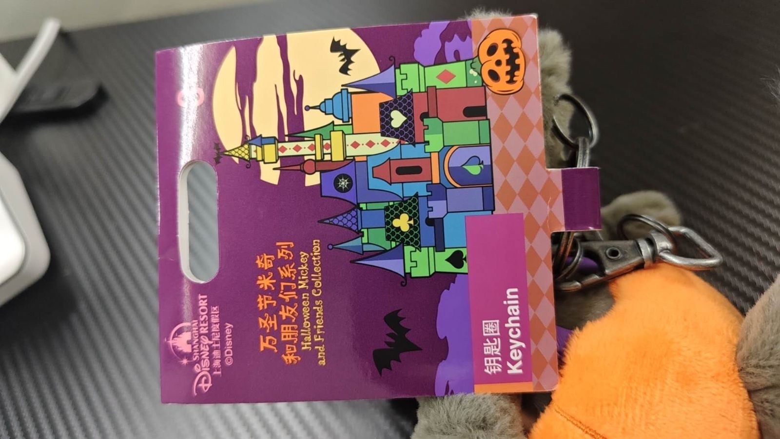 紫色の台紙タグ。ハロウィンの城とかぼちゃ、コウモリの絵があり、「万圣节米奇和朋友们系列」「Halloween Mickey and Friends Collection」「钥匙圈 Keychain」と書かれている
