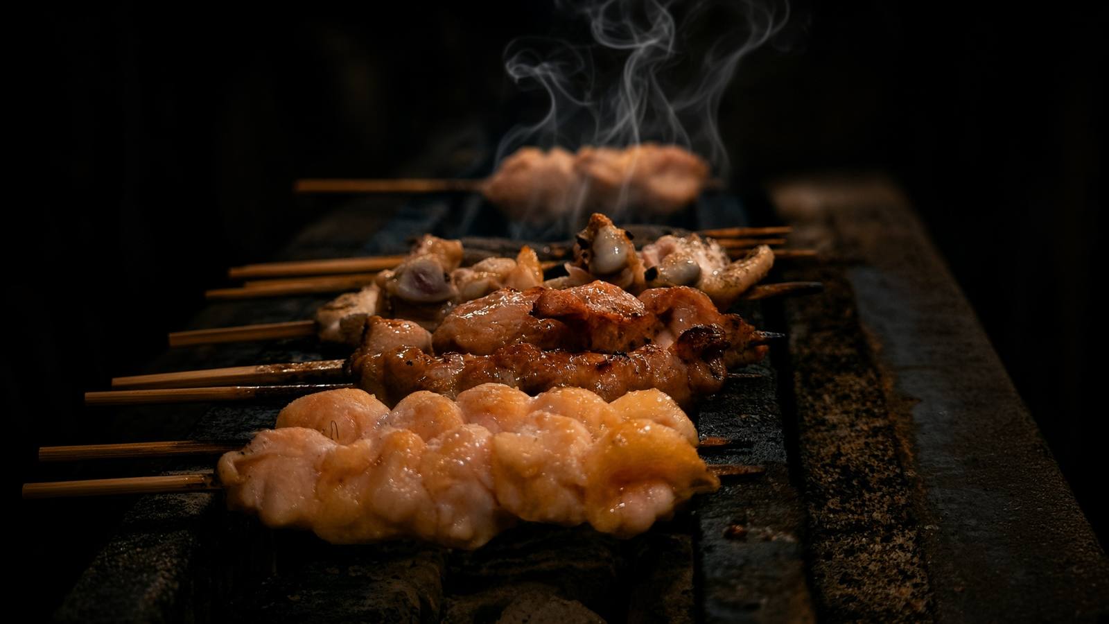 焼き台に並び、煙が立ち上る焼鳥の串