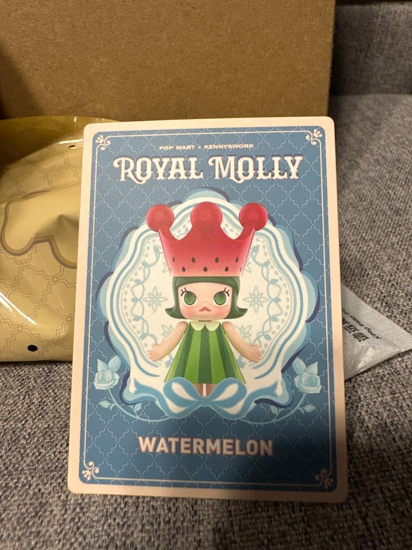 Unedited seller photograph of the WATERMELON card with a gold bag partly visible behind it