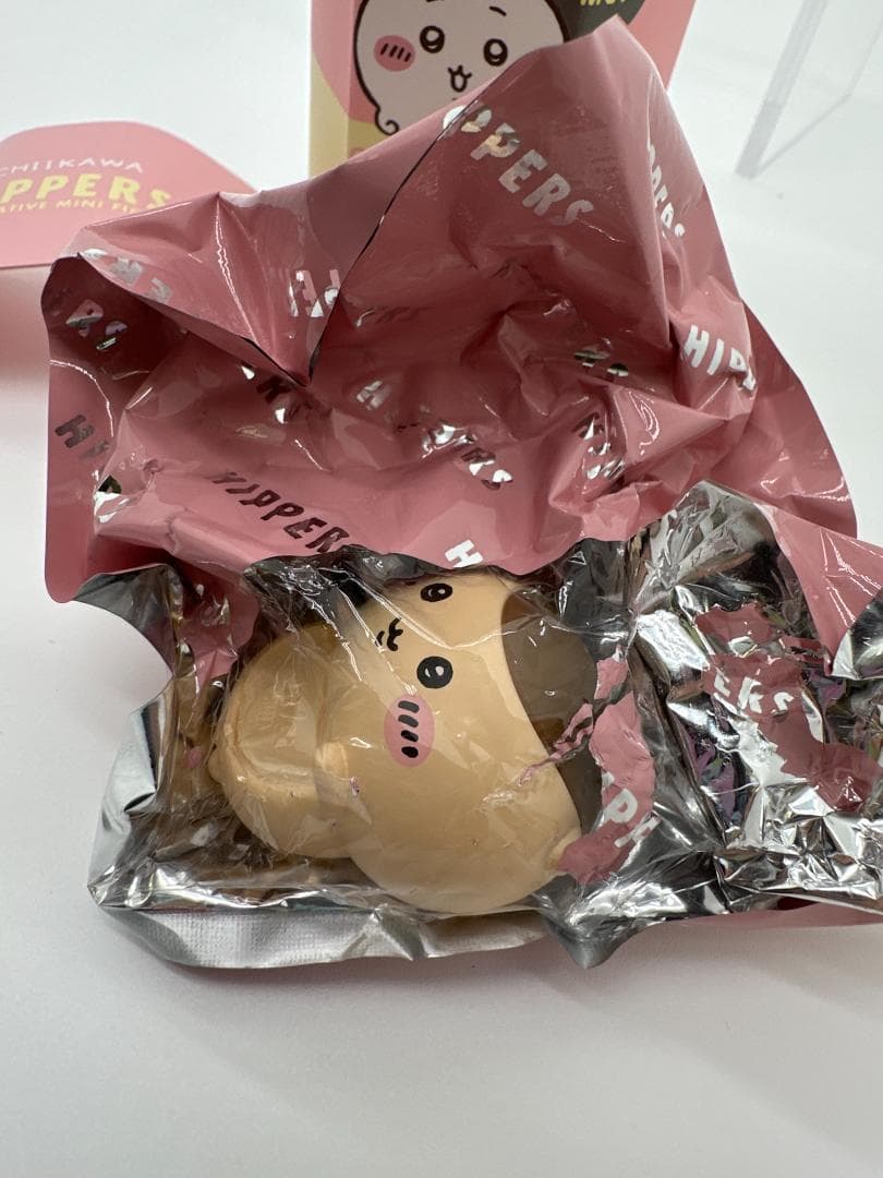 Unedited close-up of Kurimanju under clear film, surrounded by opened pink and silver packaging