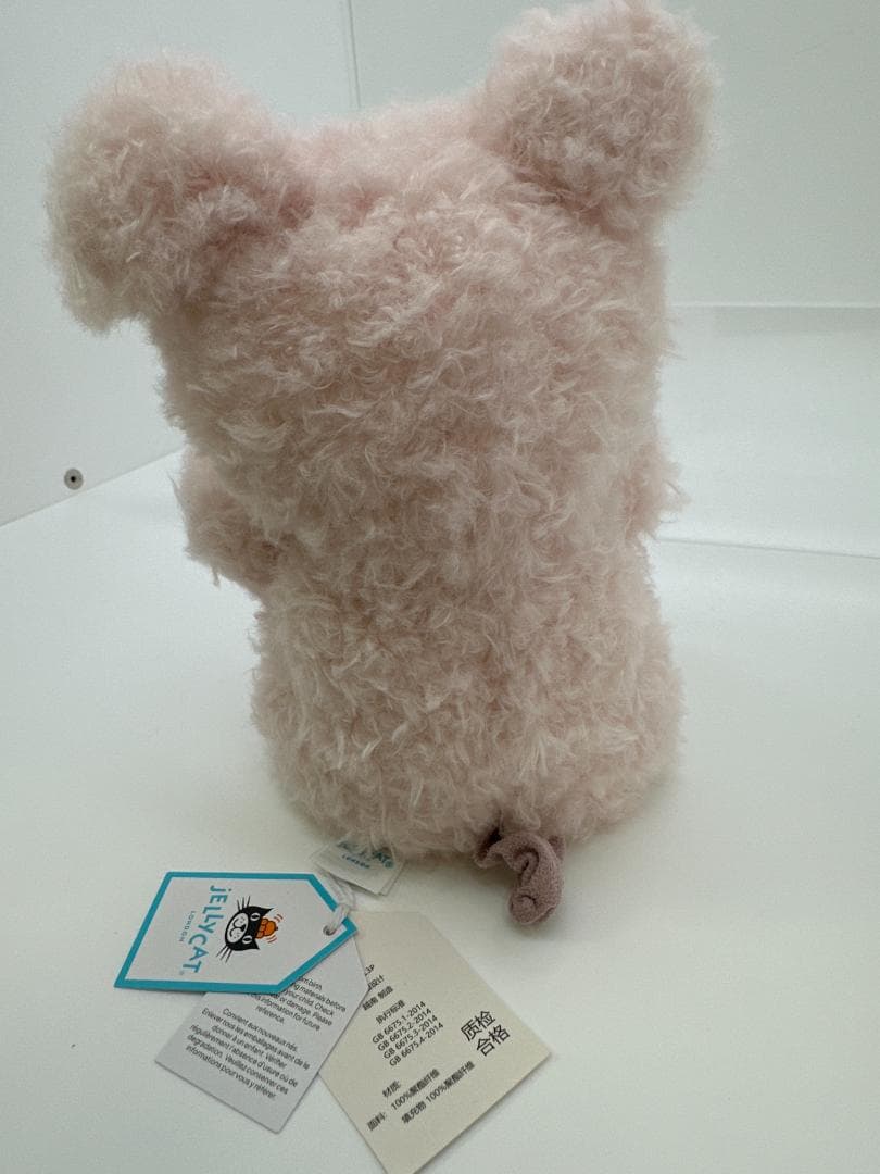 Unedited rear photo of the pig plush, showing the curled tail and attached tags