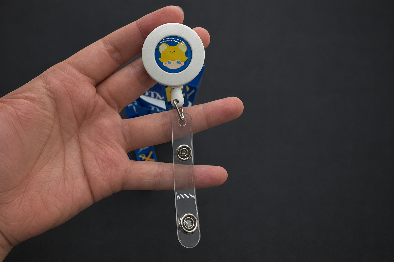 Edited close-up of the DIMOO reel and clear snap-fastening tab held in a hand