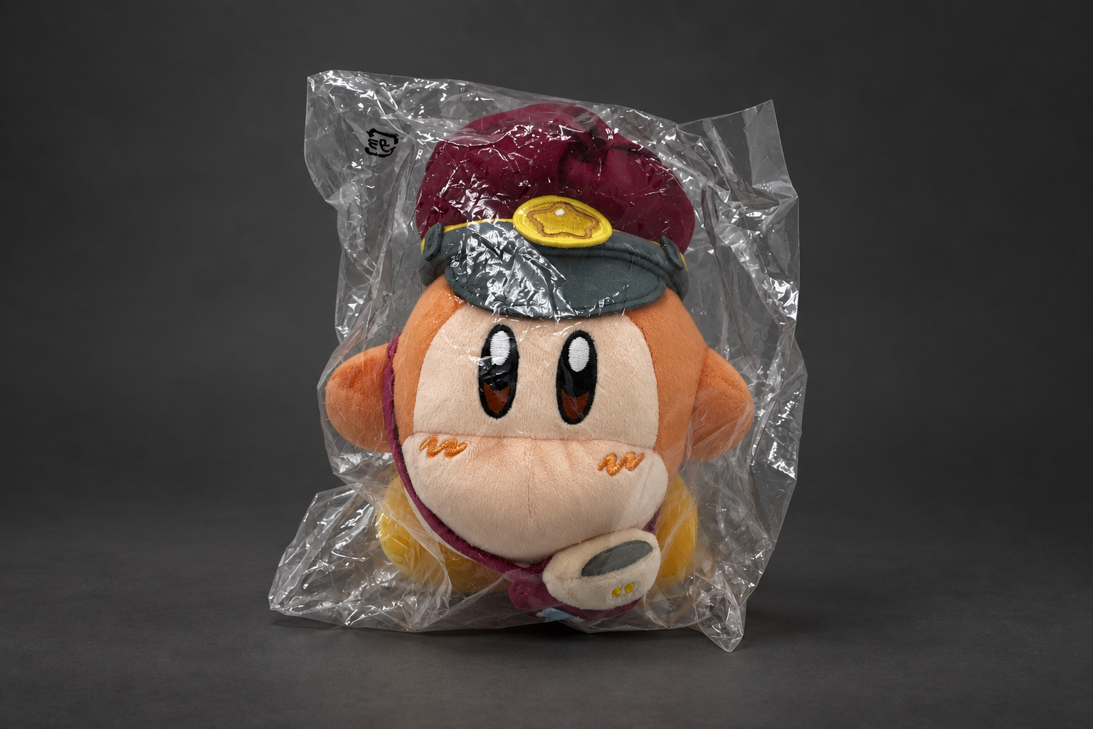 Edited photograph of a bagged Waddle Dee Hankyu plush with conductor hat and shoulder pouch